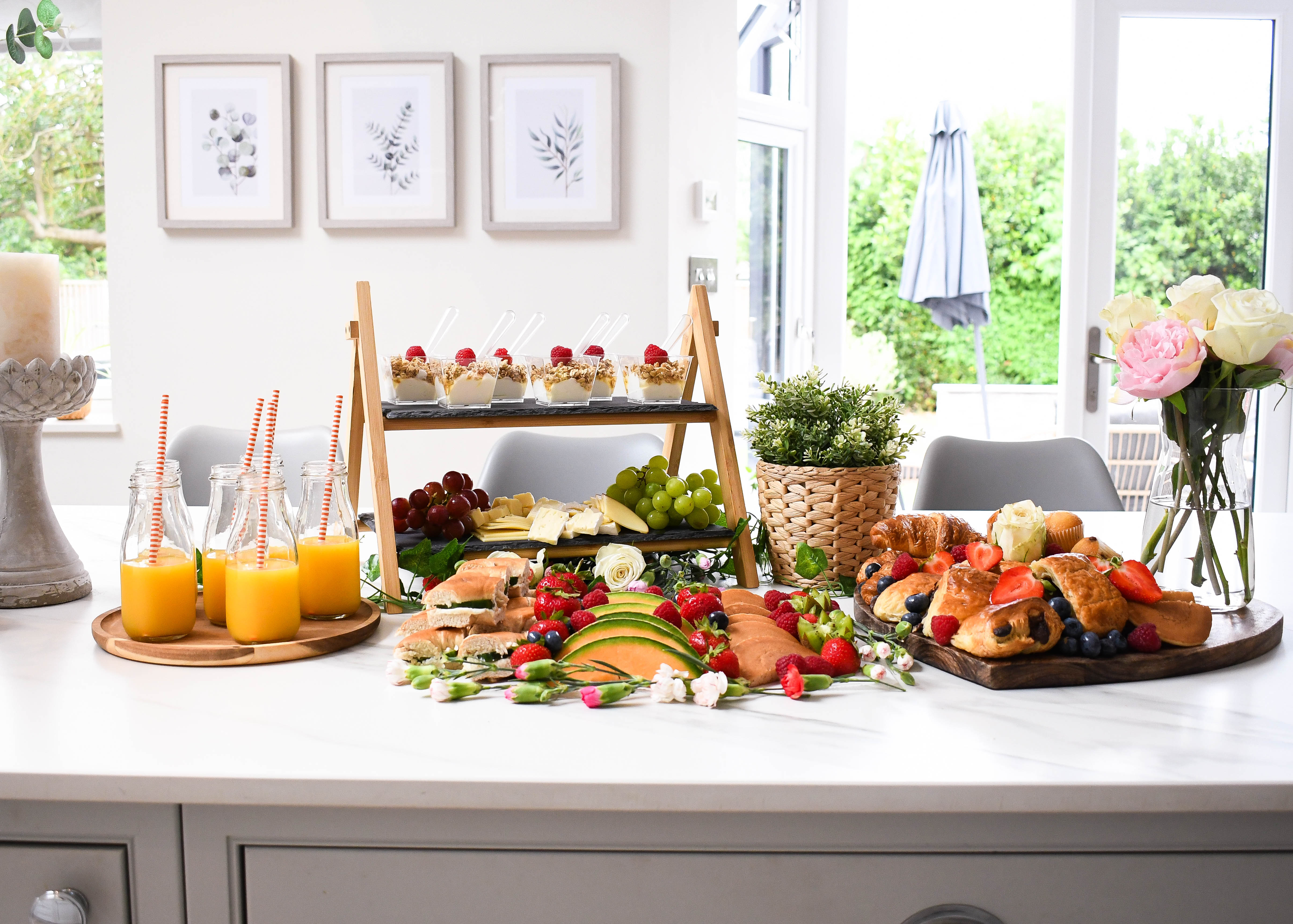 Buffet brunch table with various food items and drinks in a bright kitchen.