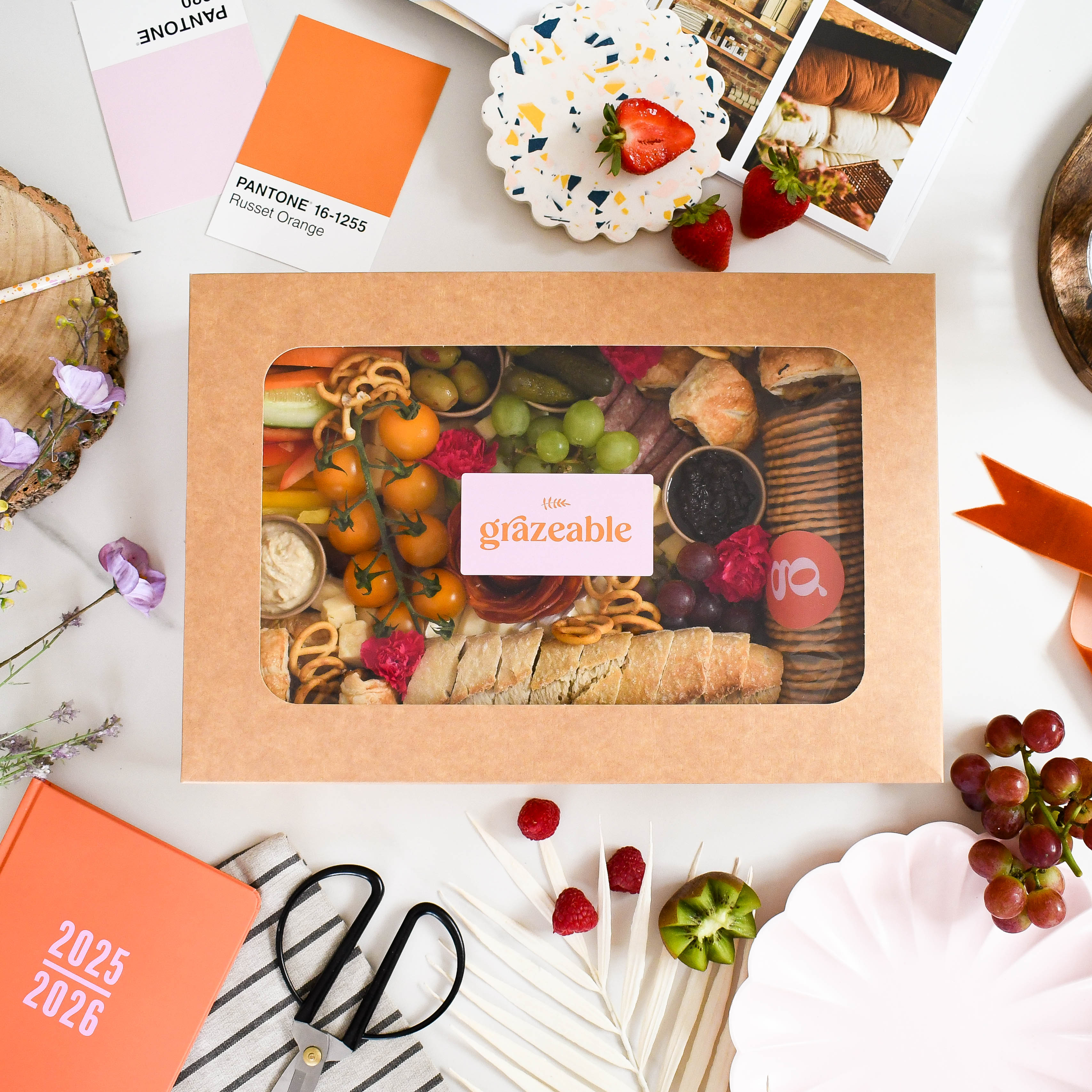 The savoury grazeable box with snacks on a white surface with decorative items.