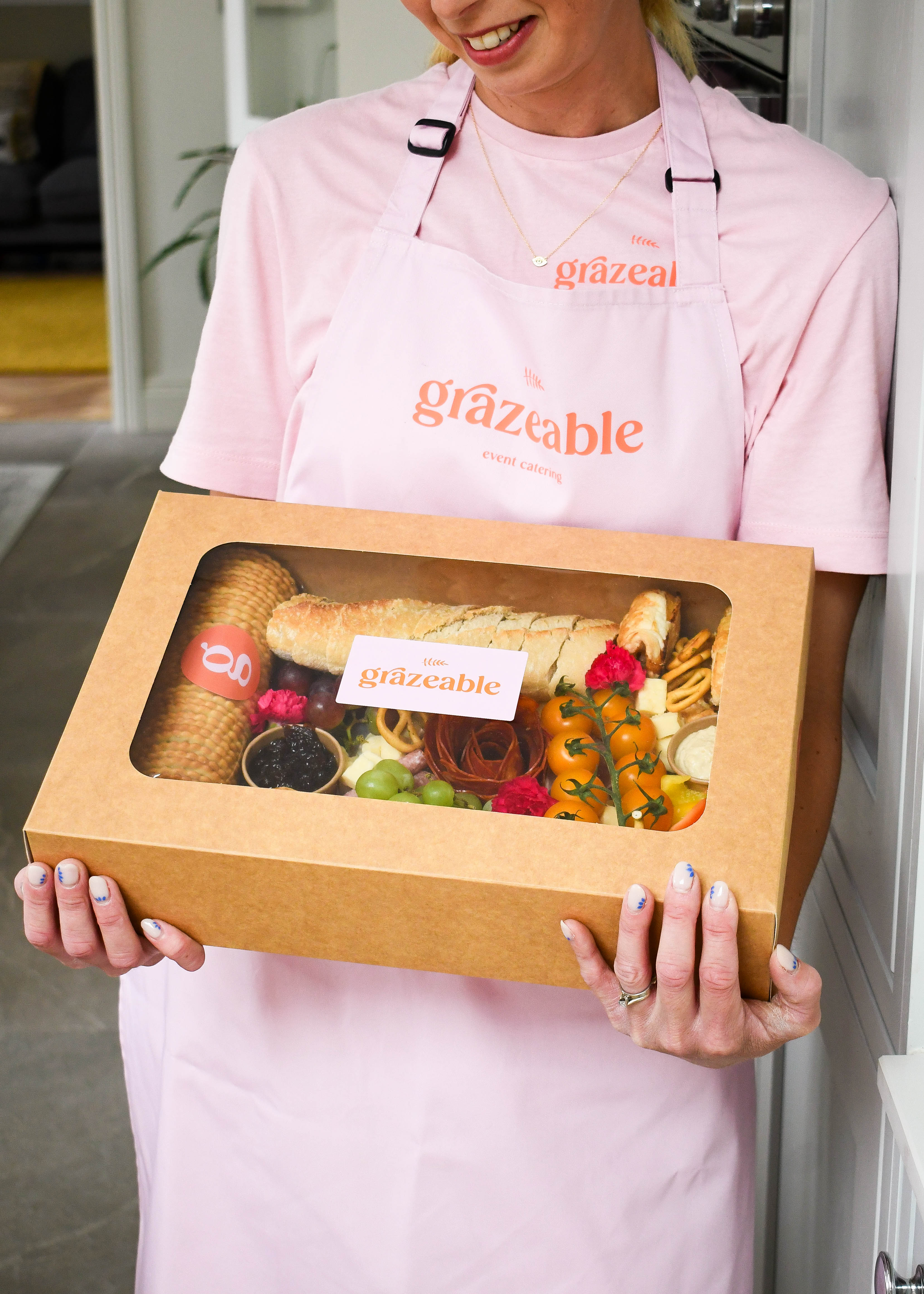 Person wearing a 'grazeable' apron holding a savoury grazeable box