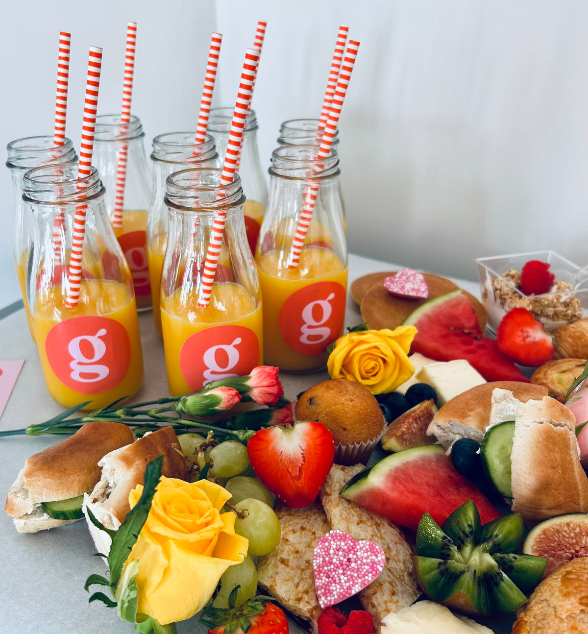 Assorted snacks and drinks with 'g' branded bottles on a table.
