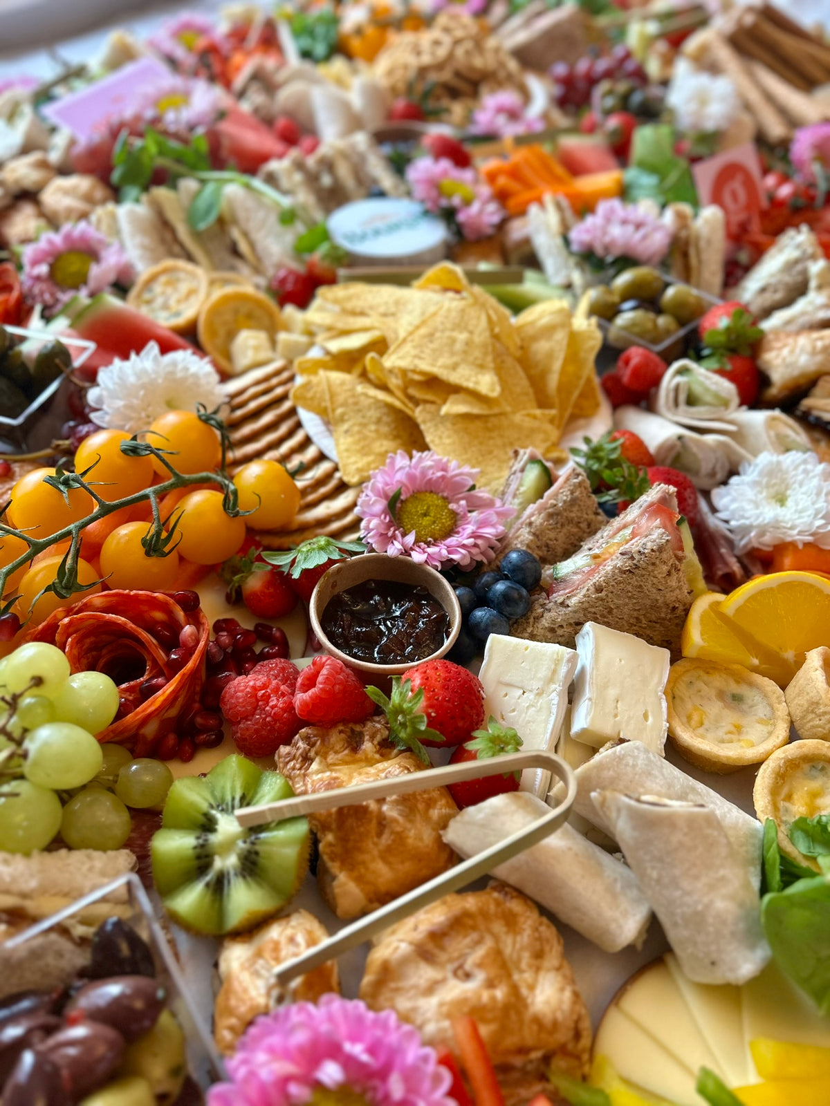 Assorted platter with fruits, meats, and cheeses on a white background