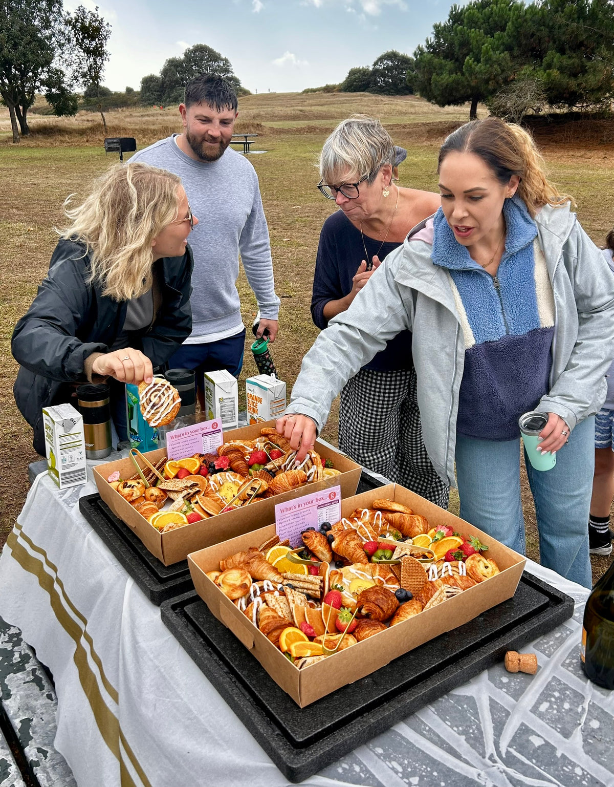 Group of people gathered around a table with food boxes outdoors