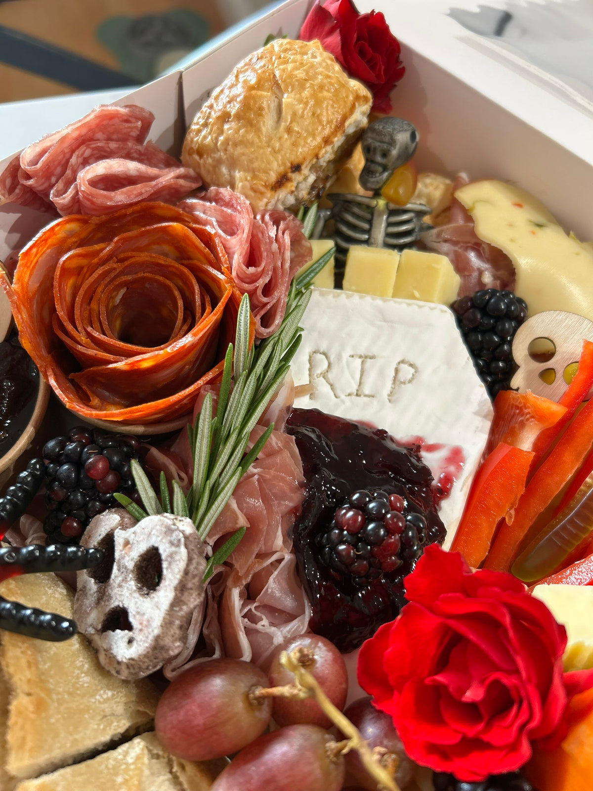 Gourmet Halloween themed charcuterie box with meats, cheeses, and fruits.