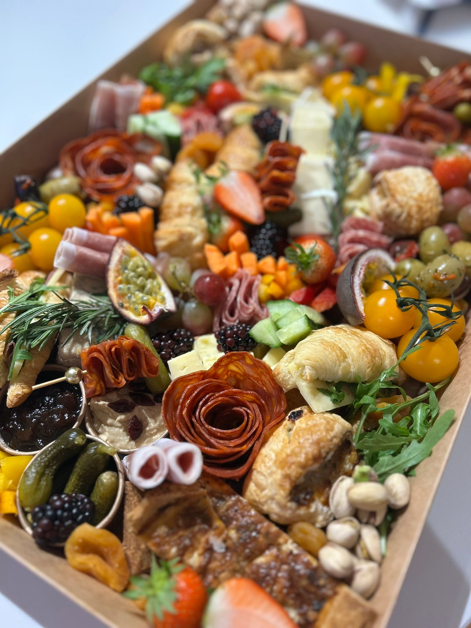 Gourmet charcuterie board with a variety of meats, cheeses, fruits, and vegetables on a wooden board.