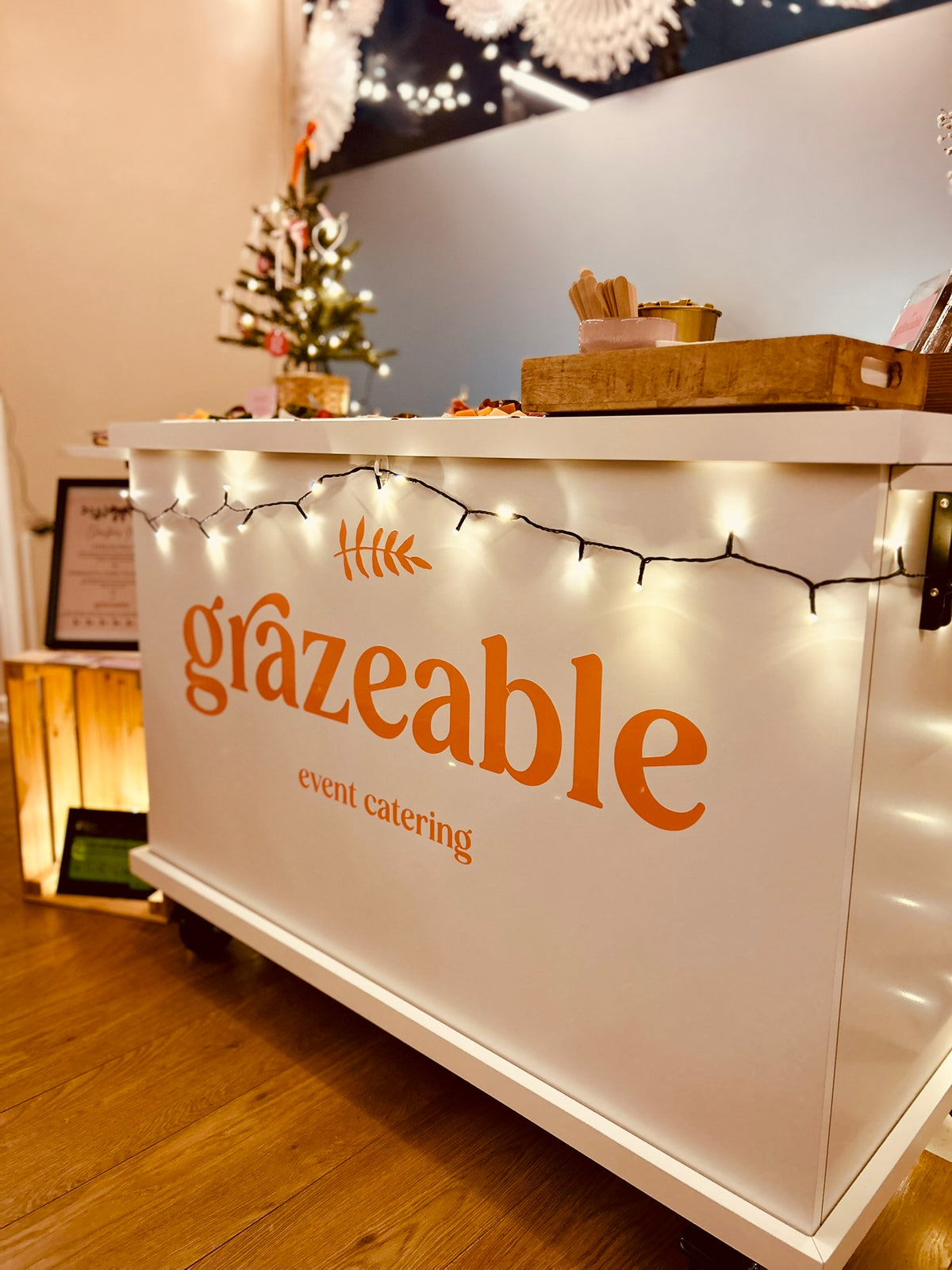 Grazeable event catering bar with decorative lights and a small Christmas tree in the background.