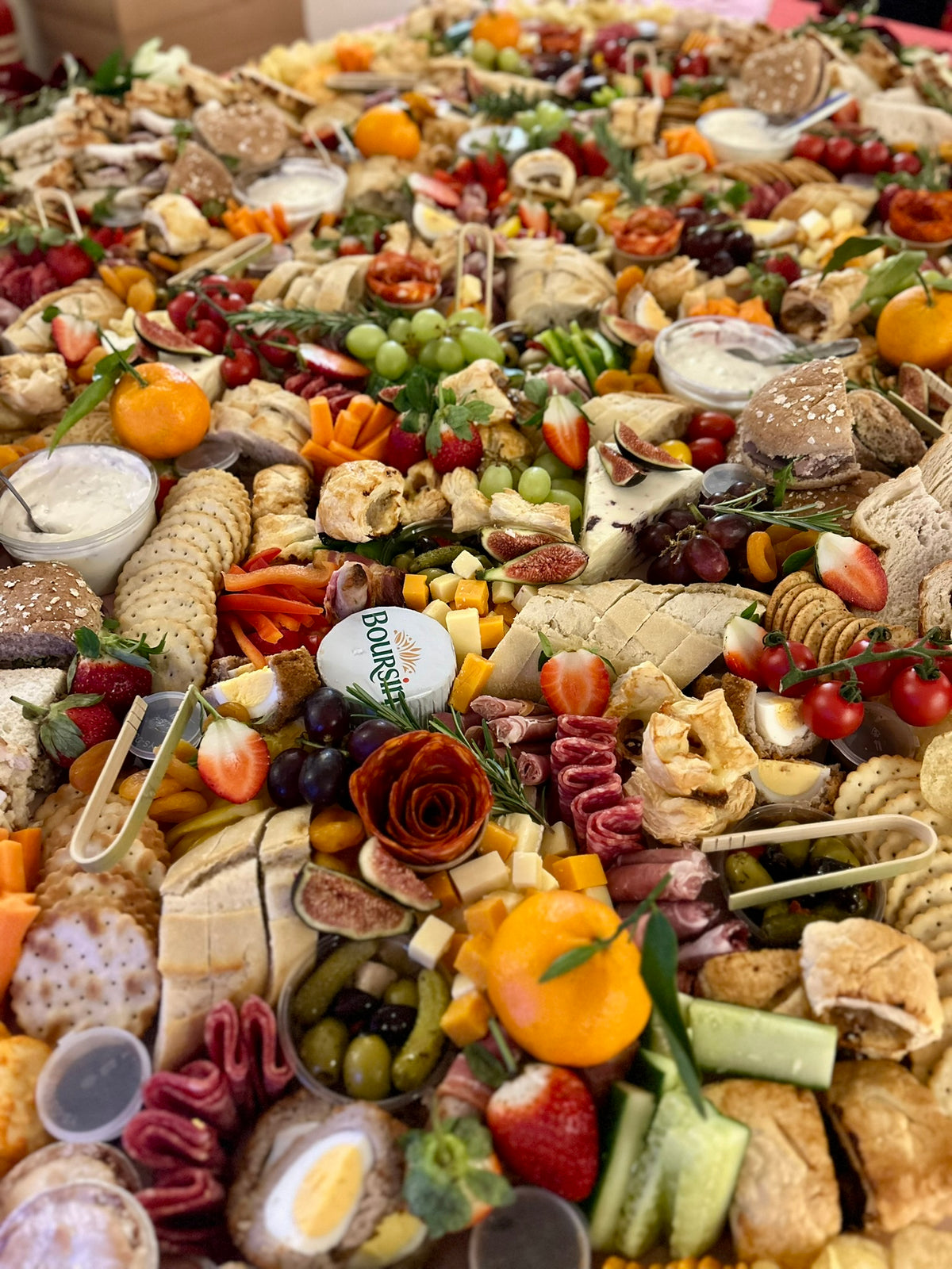 Assorted platter of meats, cheeses, fruits, and vegetables with a Boursin cheese log.