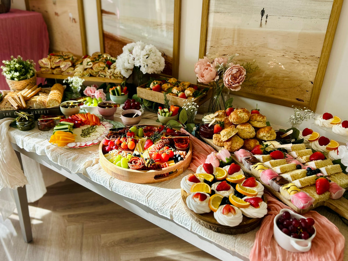 Savoury and sweet grazing table with flowers and table styling using coloured cloths in a home setting