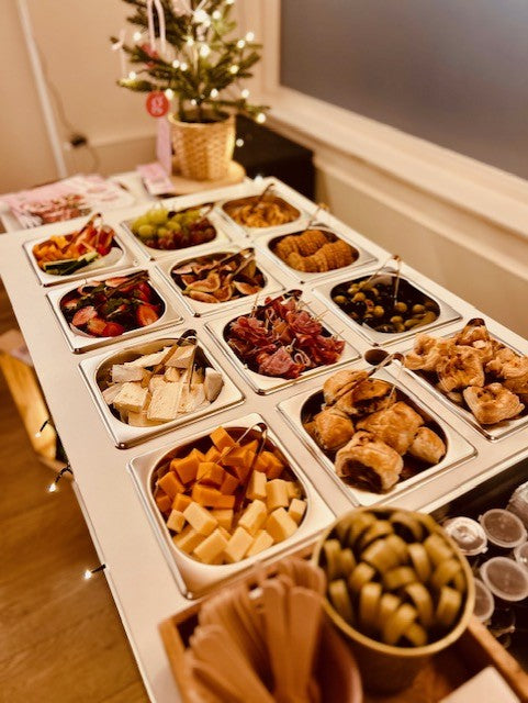 Self serve Charcuterie bar with savoury food items with small Christmas tree in background
